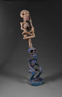 une statue représentant un squelette tenant une tête humaine au-dessus de sa propre tête