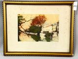 painting of a river scene in a gold frame on a white wall