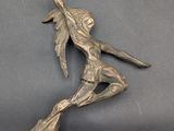 bronze statue of a woman holding a sword on top of a table