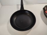 a black frying pan sitting on a counter next to a remote control
