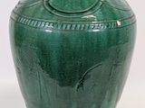 a green vase that is sitting on a white surface