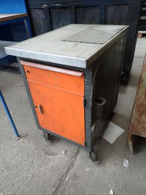 a metal table with an orange cabinet next to a metal table