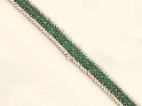 a close up of a green and white bracelet on a white surface