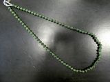 un gros plan sur un collier de perles vertes porté par un mannequin