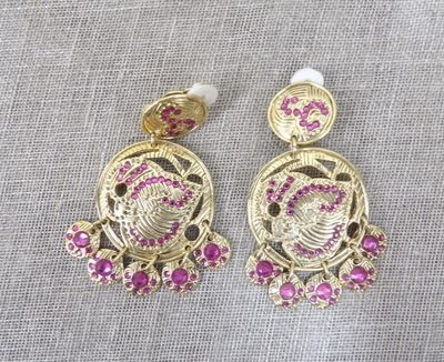 a pair of earrings with pink stones and pearls