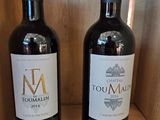 two bottles of wine sitting on a wooden shelf
