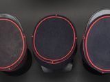 three black speakers with red trims sit on a black surface