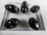 four black egg shells on a clear plate on a white surface
