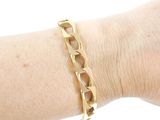 someone is wearing a gold bracelet with a chain on their arm