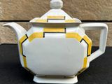 a white teapot with a yellow and black design on it