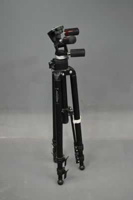 a black tripod sitting on top of a gray floor next to a camera