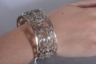 Quelqu'un porte un bracelet en argent orné d'un motif floral.