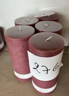 Des bougies sont alignées sur une table, avec des étiquettes de prix accrochées dessus.