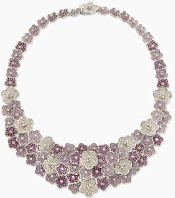 un gros plan d'un collier orné de fleurs violettes sur fond blanc
