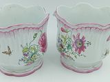 une paire de vases roses et blancs ornés de fleurs, posés sur une surface blanche