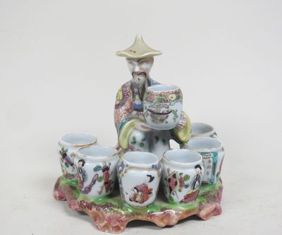 une figurine représentant un homme assis sur un plateau avec des tasses