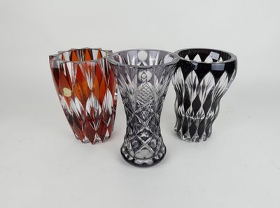 three different colored glass vases sitting next to each other on a white surface