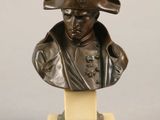 bronze bust of a man wearing a hat on a marble base