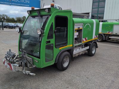 a green garbage truck parked in front of a building
