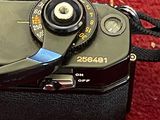 a black camera sitting on a red carpet next to a camera strap
