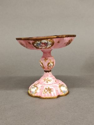 a small pink vase with a gold rim on a table