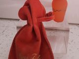 un flacon de parfum dans une pochette en velours rouge, avec un bouchon doré
