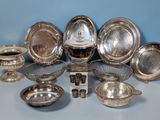 silver plated dishes and bowls on a table with a blue wall in the background