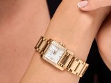La femme porte une montre-bracelet en or et un t-shirt noir.