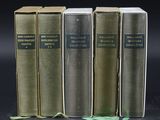 three old books are lined up on a black surface