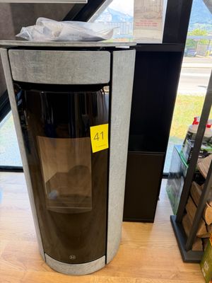 une poubelle noire et argentée sur laquelle est collé un autocollant jaune