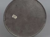 an old silver plate with a sticker on it sitting on a table