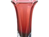 un vase en verre rouge bordé de noir, posé sur une surface blanche