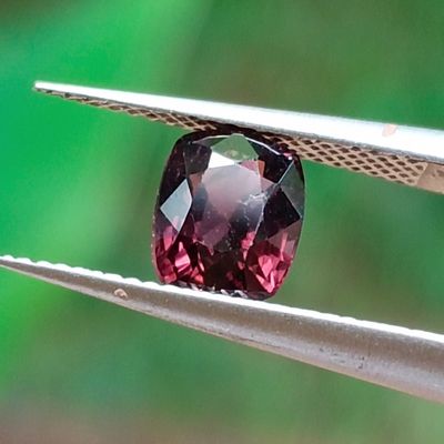 un gros plan d'un diamant rouge tenu par une pince