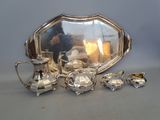 a silver tray with a mirror and silver tea set on a table