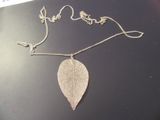 pendentif en feuille d'argent suspendu à une chaîne en argent sur un fond noir