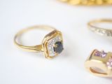three different rings and a ring with a blue stone on a white surface