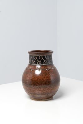 un vase brun posé sur une table à fond blanc