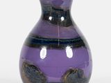 un vase violet posé sur une table, sur fond blanc