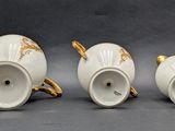 three white and gold teapots sitting next to each other on a table