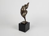 une statue en bronze représentant une femme, posée sur un socle noir