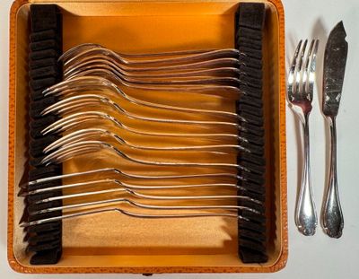 plusieurs fourchettes et cuillères dans un étui, ainsi qu'une fourchette et un couteau posés sur une table