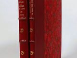 two red books sitting on top of each other on a white surface