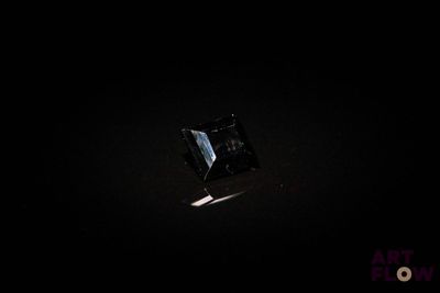 une image représentant un diamant noir dans l'obscurité, éclairé par une source lumineuse