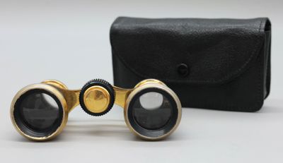 une vieille paire de jumelles posée sur un étui noir