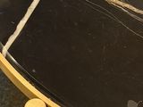 a black marble table with gold legs and a black top