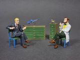 two figurines of a man and a woman sitting in a chair