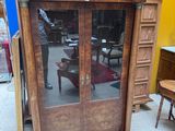 a wooden cabinet with glass doors in the middle of a room