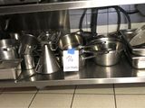 de nombreuses casseroles et poêles posées sur une étagère en acier inoxydable