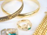 many gold rings and bracelets on a white surface