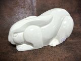 a white rabbit figurine sitting on a brown surface